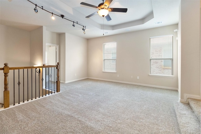 unfurnished room with carpet floors, track lighting, ceiling fan, and a tray ceiling