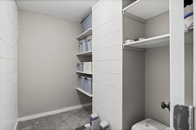 bedroom with ceiling fan, wooden walls, carpet, and a textured ceiling