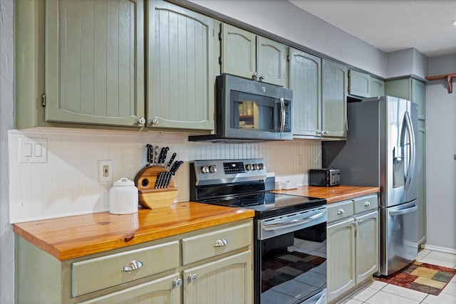 kitchen with butcher block countertops, light tile patterned floors, stainless steel appliances, and green cabinets