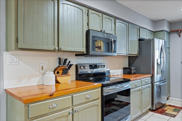 kitchen featuring wood counters, sink, light tile patterned floors, appliances with stainless steel finishes, and pendant lighting