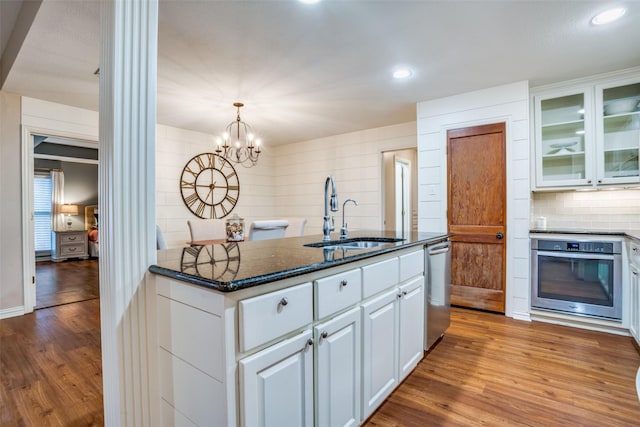 kitchen with stainless steel appliances, white cabinetry, sink, and light hardwood / wood-style floors