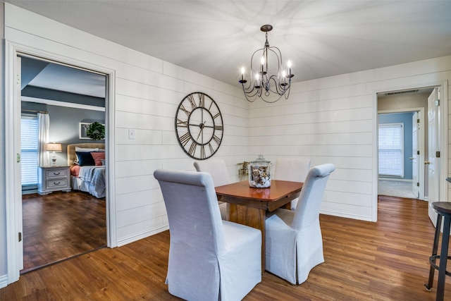 dining area with dark hardwood / wood-style floors and an inviting chandelier