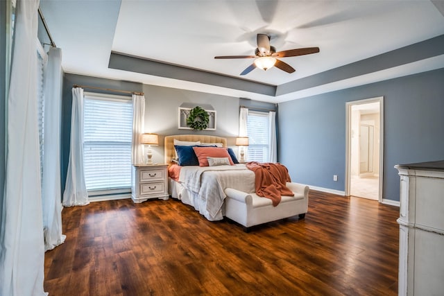 bedroom featuring dark wood-type flooring, a raised ceiling, and ceiling fan