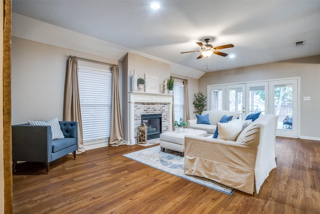 living room featuring lofted ceiling, ceiling fan, a fireplace, wood-type flooring, and french doors