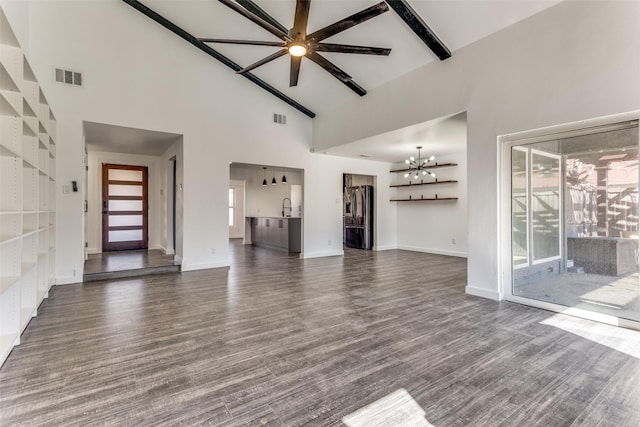 unfurnished living room featuring dark wood-type flooring, sink, a notable chandelier, and high vaulted ceiling