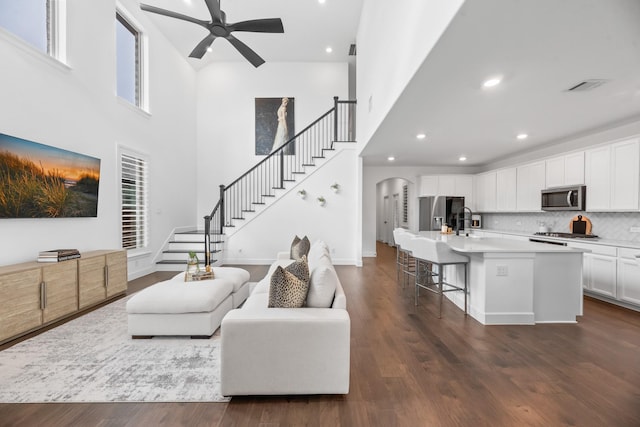 living area with dark wood finished floors, stairway, visible vents, and arched walkways