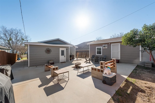 rear view of property featuring a patio, an outbuilding, and a fire pit