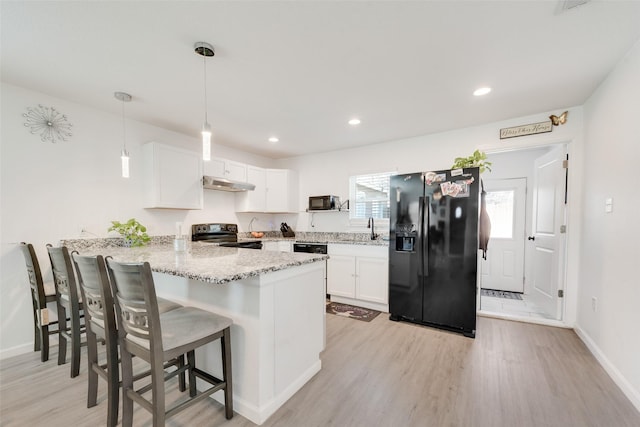 kitchen with hanging light fixtures, black appliances, white cabinets, a kitchen bar, and kitchen peninsula