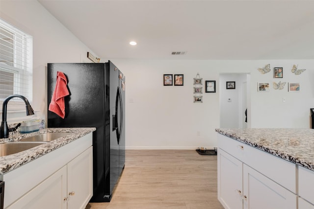 kitchen featuring sink, light stone countertops, and white cabinets