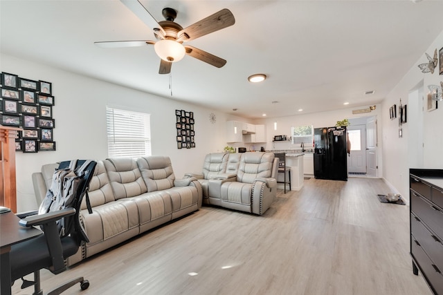 living room with light hardwood / wood-style flooring and ceiling fan