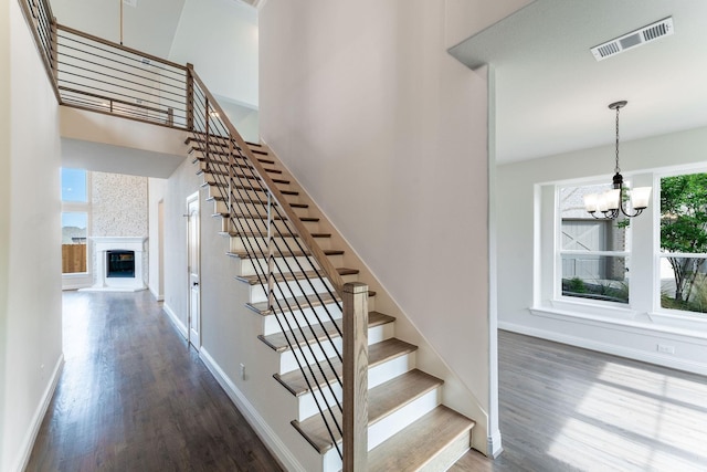 stairway with hardwood / wood-style floors and a notable chandelier