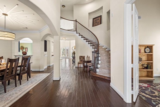 entrance foyer with a high ceiling, baseboards, ornamental molding, stairway, and wood-type flooring