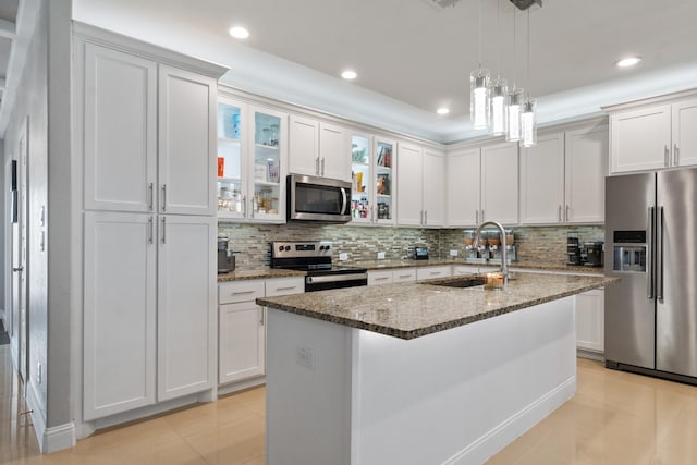 kitchen with white cabinetry, appliances with stainless steel finishes, sink, and a kitchen island with sink