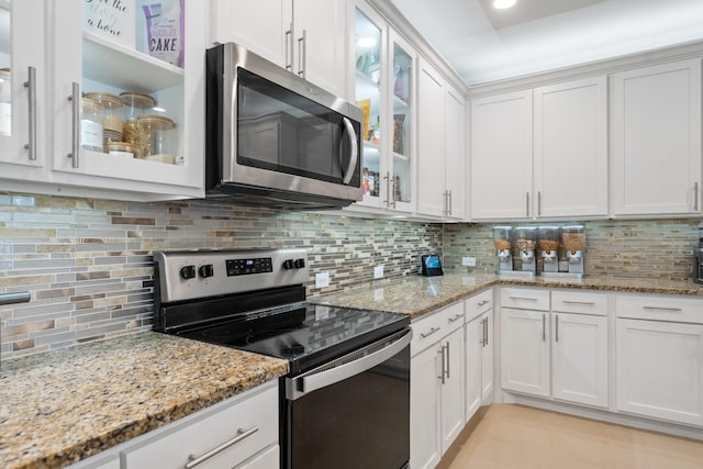 kitchen with appliances with stainless steel finishes, tasteful backsplash, white cabinetry, light tile patterned floors, and light stone counters