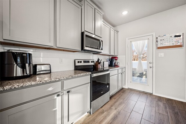 kitchen with light stone countertops, appliances with stainless steel finishes, and backsplash