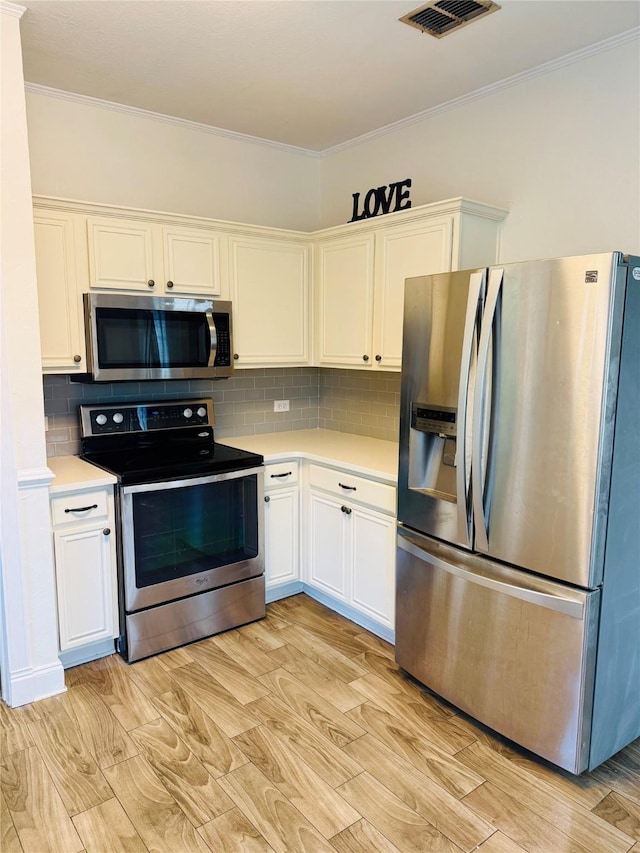 kitchen featuring stainless steel appliances, tasteful backsplash, white cabinets, and crown molding