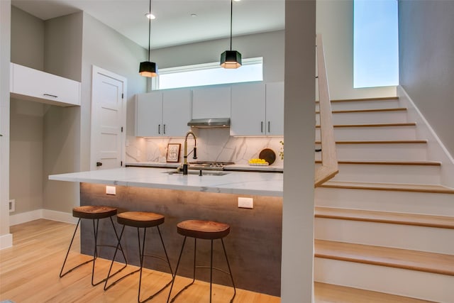 kitchen with white cabinetry, sink, decorative light fixtures, and backsplash