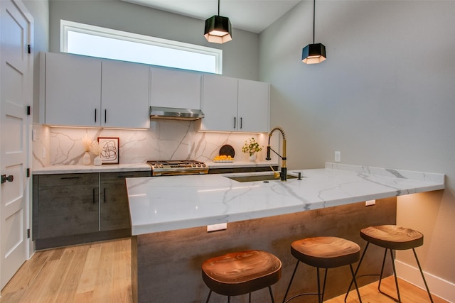 kitchen with sink, a breakfast bar, kitchen peninsula, and decorative light fixtures