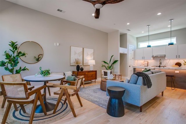 living room featuring a towering ceiling, light hardwood / wood-style floors, and sink