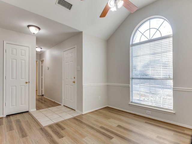 empty room with vaulted ceiling, ceiling fan, and light wood-type flooring