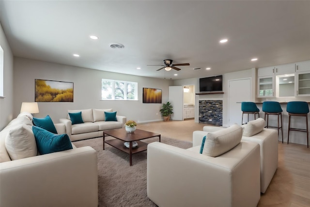 living room featuring a stone fireplace and ceiling fan