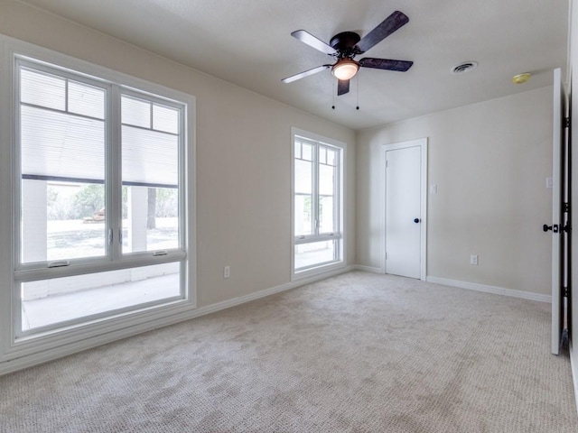 carpeted empty room featuring ceiling fan and a wealth of natural light