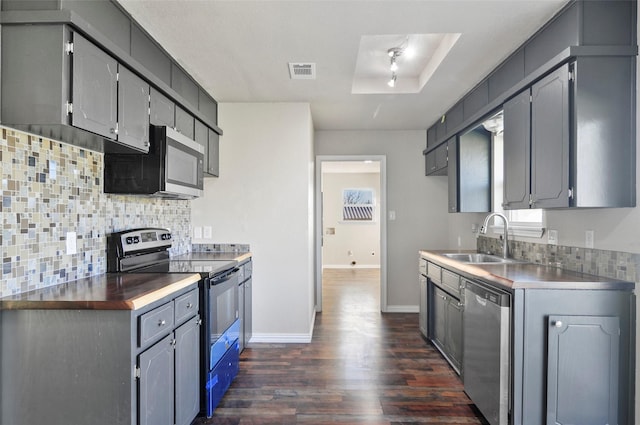 kitchen with sink, tasteful backsplash, appliances with stainless steel finishes, dark hardwood / wood-style flooring, and a raised ceiling