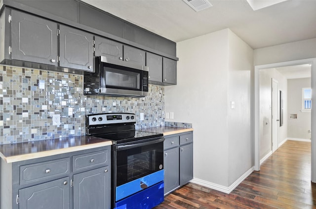 kitchen with stainless steel appliances, gray cabinets, dark hardwood / wood-style floors, and decorative backsplash