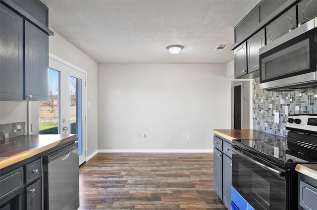 kitchen with butcher block counters, backsplash, stainless steel appliances, dark hardwood / wood-style floors, and french doors