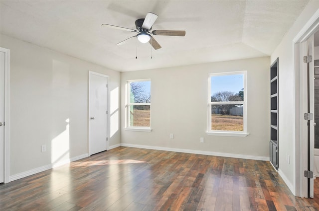 spare room with dark wood-type flooring, a wealth of natural light, and ceiling fan