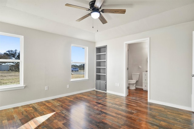 unfurnished bedroom with dark wood-type flooring, ceiling fan, and connected bathroom