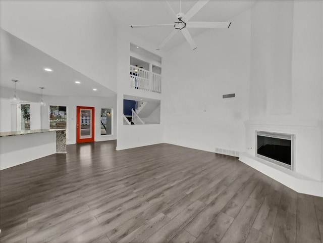 unfurnished living room featuring hardwood / wood-style flooring, ceiling fan, and a high ceiling