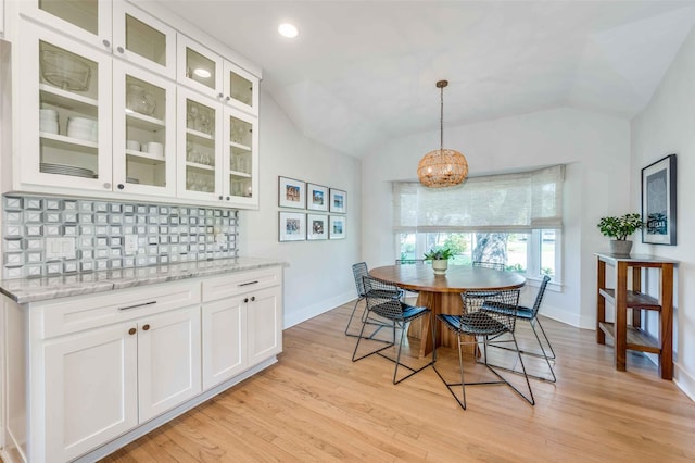 dining room featuring lofted ceiling, light hardwood / wood-style flooring, and a notable chandelier