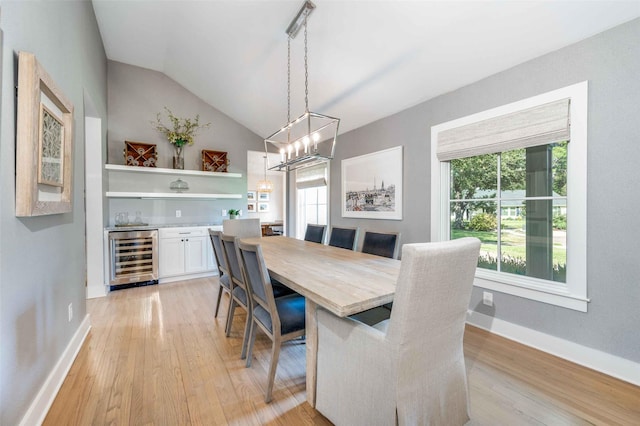 dining space featuring a notable chandelier, lofted ceiling, wine cooler, and light wood-type flooring