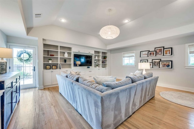 living room with light hardwood / wood-style flooring, built in shelves, and vaulted ceiling