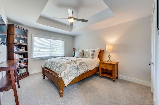 bedroom featuring ceiling fan, light colored carpet, and a raised ceiling