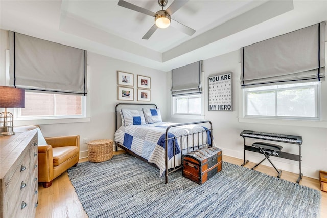 bedroom with a tray ceiling, light hardwood / wood-style flooring, and ceiling fan