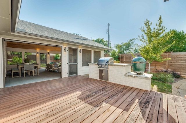 wooden deck with area for grilling, a patio area, and exterior kitchen