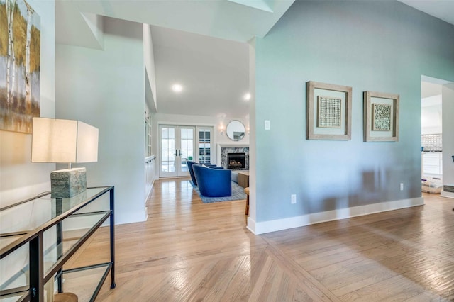 corridor with light hardwood / wood-style floors, high vaulted ceiling, and french doors