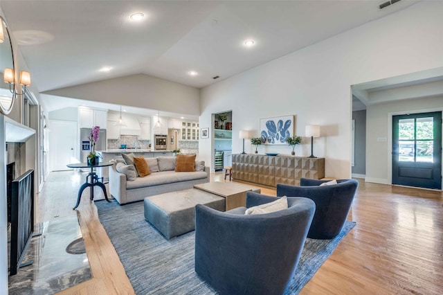 living room with high vaulted ceiling and light hardwood / wood-style floors