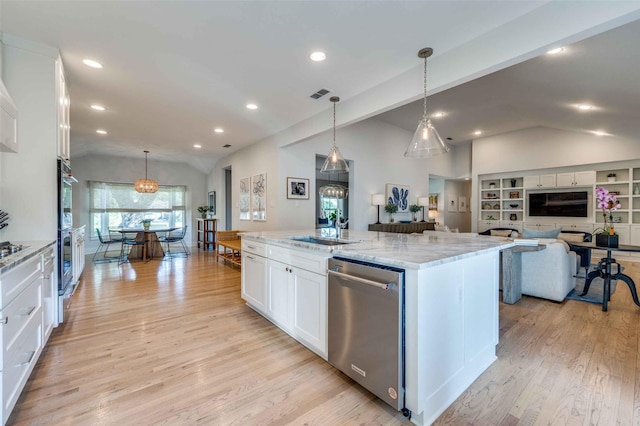 kitchen featuring decorative light fixtures, stainless steel appliances, a large island, light stone countertops, and white cabinets