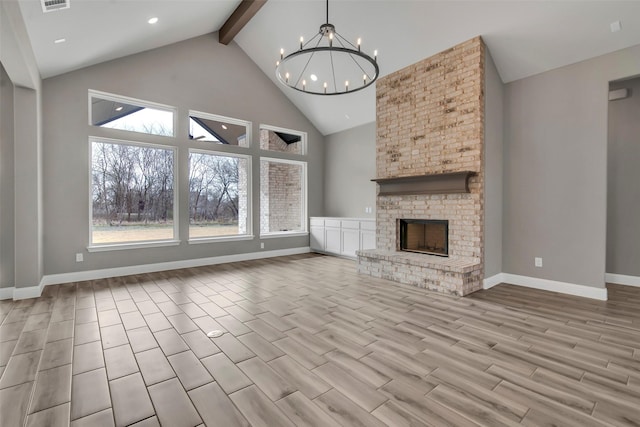 unfurnished living room featuring high vaulted ceiling, a notable chandelier, a brick fireplace, beamed ceiling, and light wood-type flooring