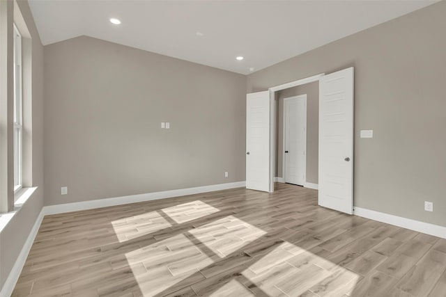 unfurnished bedroom with vaulted ceiling and light hardwood / wood-style floors