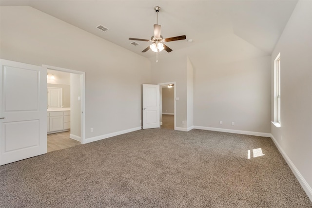 unfurnished bedroom featuring ceiling fan, high vaulted ceiling, light carpet, and ensuite bath