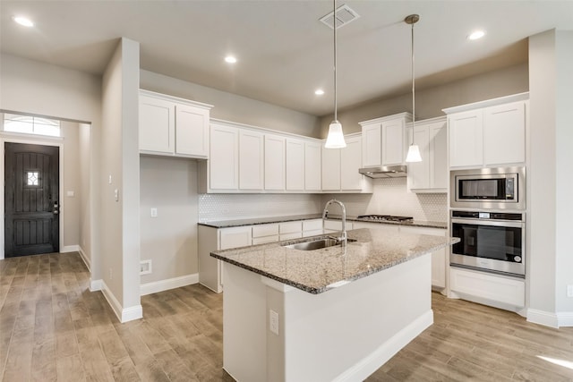 kitchen with light stone counters, sink, stainless steel appliances, and white cabinets