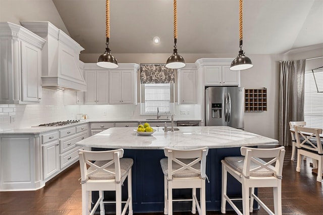 kitchen featuring stainless steel appliances, lofted ceiling, white cabinetry, and custom exhaust hood