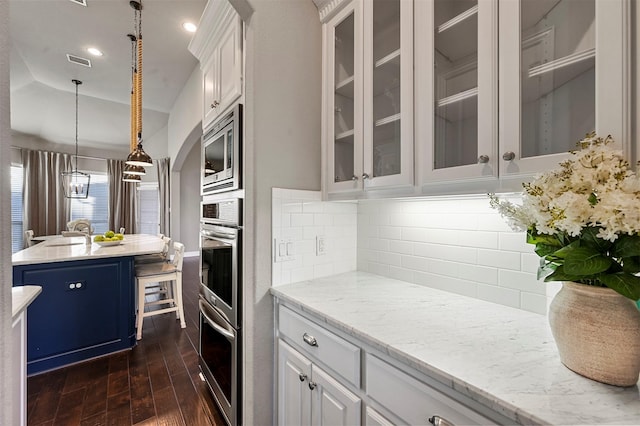 kitchen with visible vents, white cabinets, stainless steel microwave, dark wood-type flooring, and backsplash