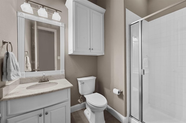 bathroom with toilet, a stall shower, baseboards, and vanity