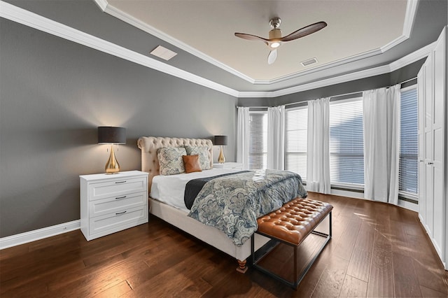 bedroom featuring crown molding, dark wood finished floors, a raised ceiling, visible vents, and baseboards