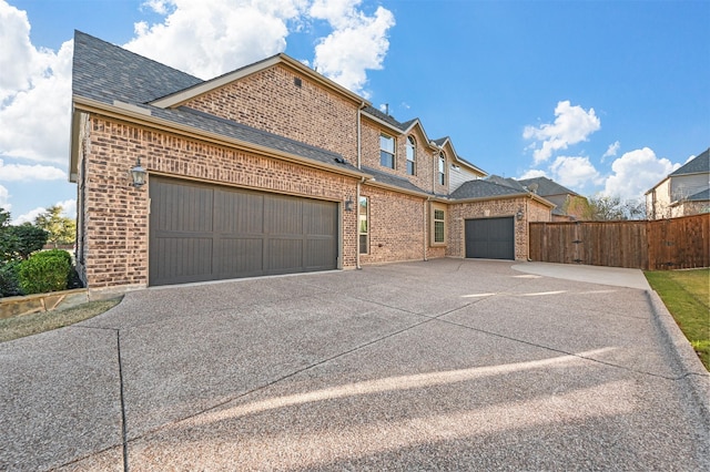 view of front facade with a shingled roof, concrete driveway, an attached garage, fence, and brick siding